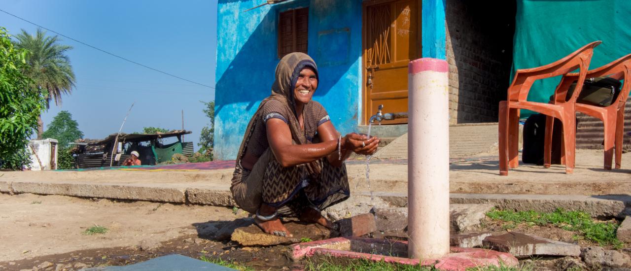 A woman in Dharampuri village in Madhya Pradesh, India proudly demonstrates using a spigot outside her home newly built as a result of the USAID Gap Inc. Women + Water Alliance’s village action planning and coordination with Indian government initiatives.